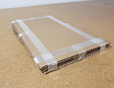 paper secured in between 2 layers of cardboard, taped together